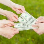 Business people hands exchanging money, closeup shot on natural green background